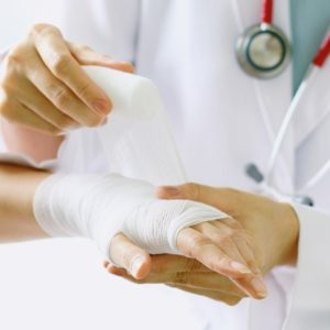 doctor wrapping bandage around patient's hand and wrist